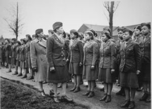 A group of African American women, in WWII military uniforms, stand at attention.