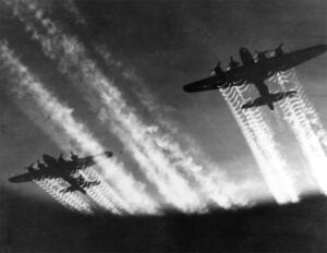 Two B-17 Flying Fortress airplanes' vapor trails are streaks thru the night sky.
