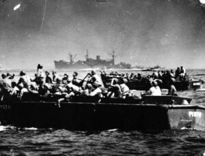 Amphibious landing craft full of WWII servicemembers in the water